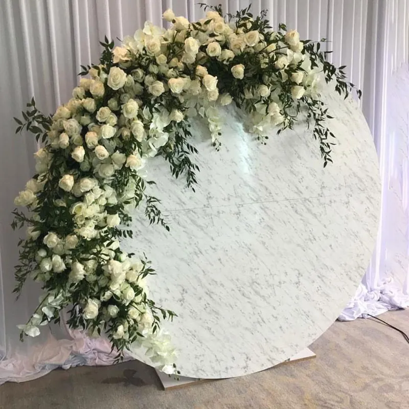 The Circular Marble Backdrop, a large round marble design with white roses and greenery, set against white draped curtains