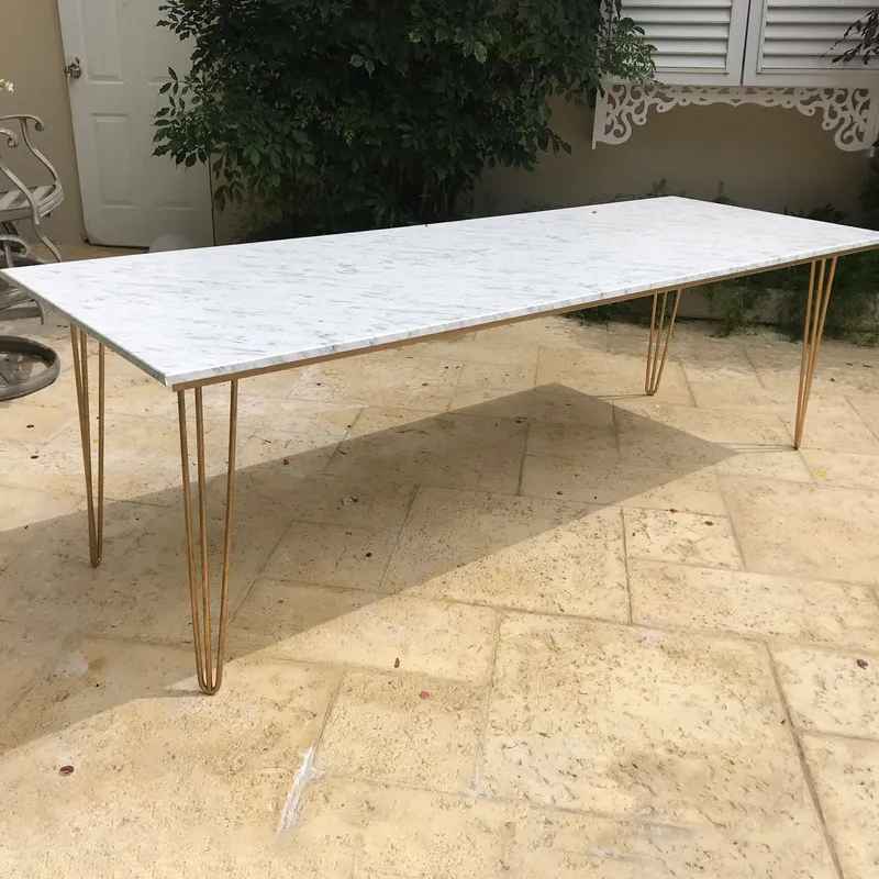 Marble Hairpin Table with a white marble-effect top and slim gold metal hairpin legs on a beige tiled patio