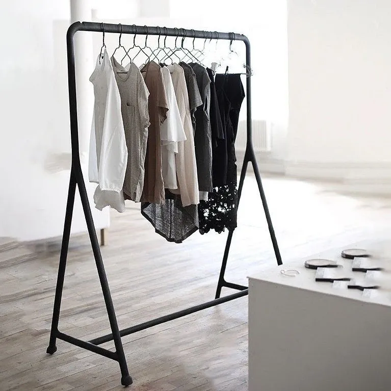 Mobile Clothing Rack holding neutral shirts and tops on hangers in a minimalist, well-lit room with wooden floors