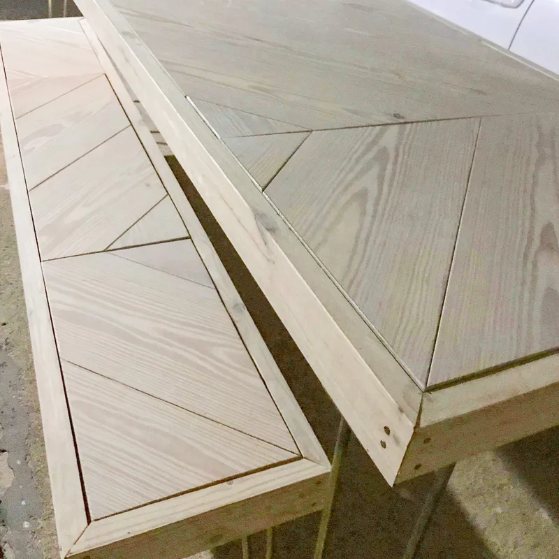 Hairpin Sweetheart Table, two unfinished tables with geometric chevron-patterned tops side by side on a concrete floor