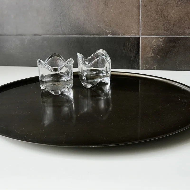 The Candle Tray with two small, clear glass candle holders on a round black tray