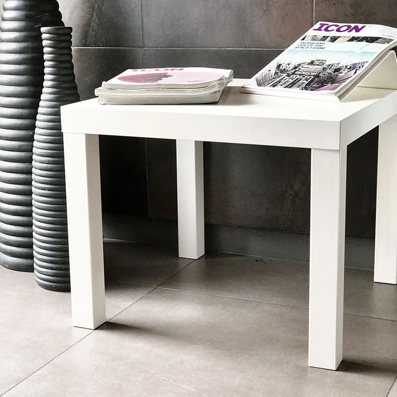 Simple Side Table, white and rectangular, holding stacked magazines on a tiled floor beside a tall, textured black vase
